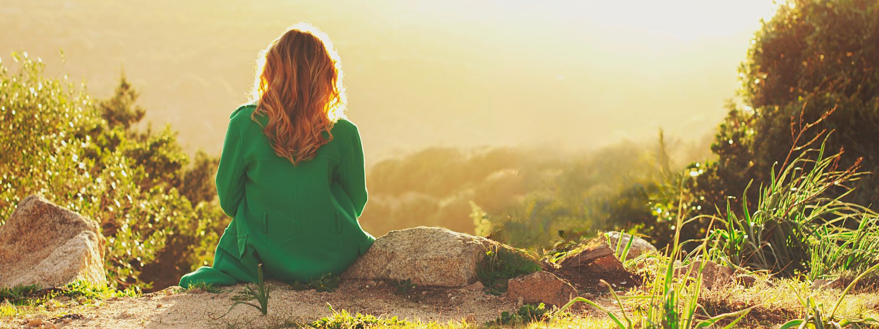 a woman outside looking at the sunset with hills scenery